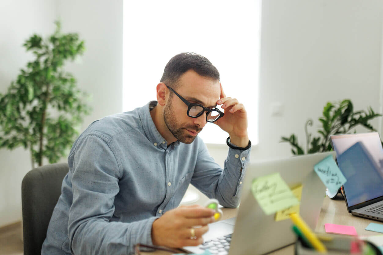 Homem adulto concentrado em frente ao computador com expressão de esforço mental, ilustrando os desafios enfrentados por adultos com TDAH no ambiente de trabalho.